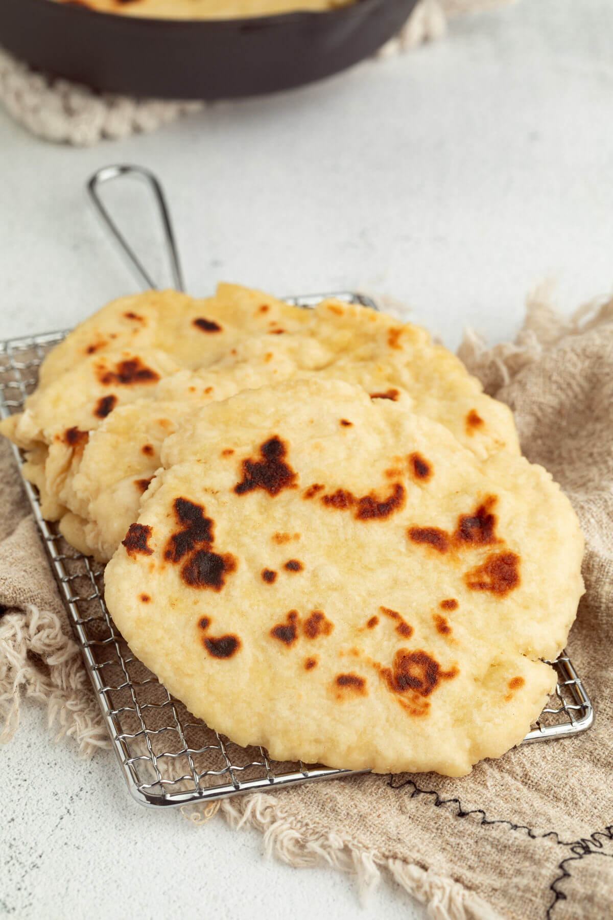 Sourdough naan in a stack on a wire cooling rack.
