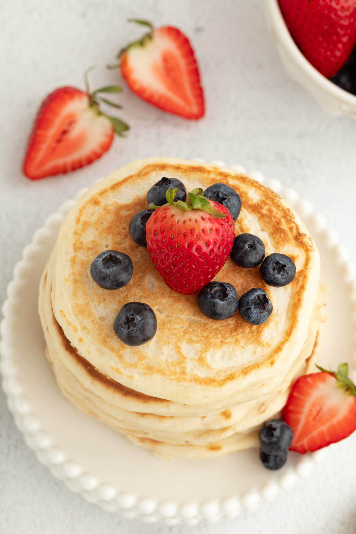 Fluffy sourdough pancakes with fresh strawberries and blueberries on top.