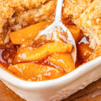 Sourdough peach cobbler in a baking dish with a spoon for serving.