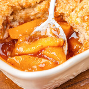 Sourdough peach cobbler in a baking dish with a spoon for serving.