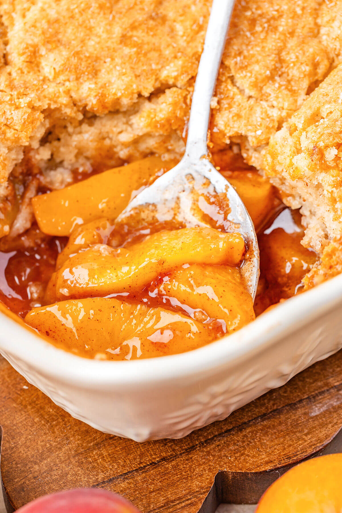 Photo of a spoon lifting up the sourdough peach cobbler filling.