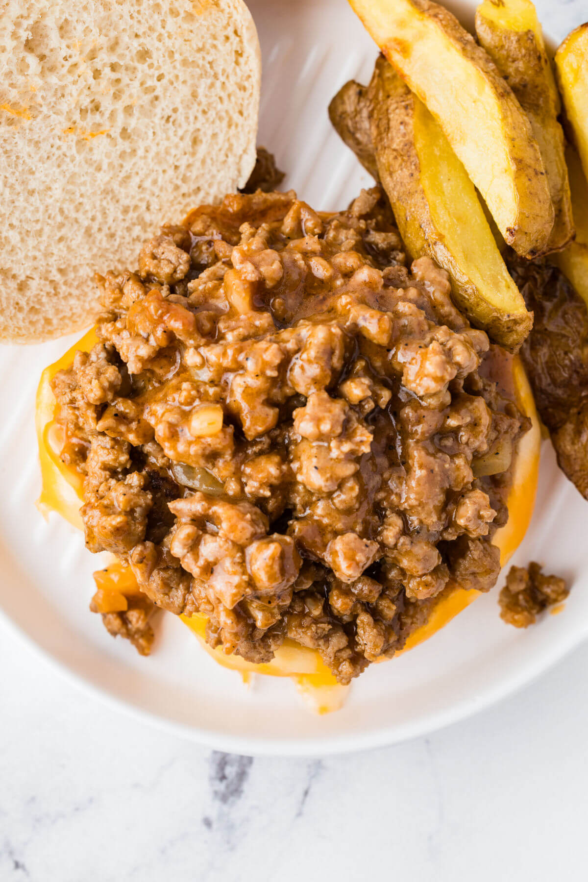 Adding turkey sloppy joe filling to hamburger buns.