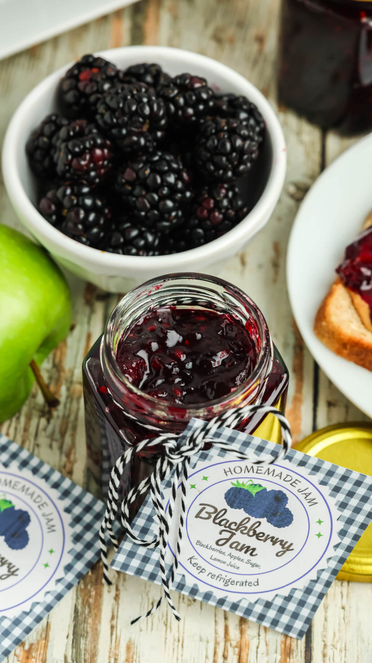A bowl of blackberries next to a jar of blackberry freezer jam.