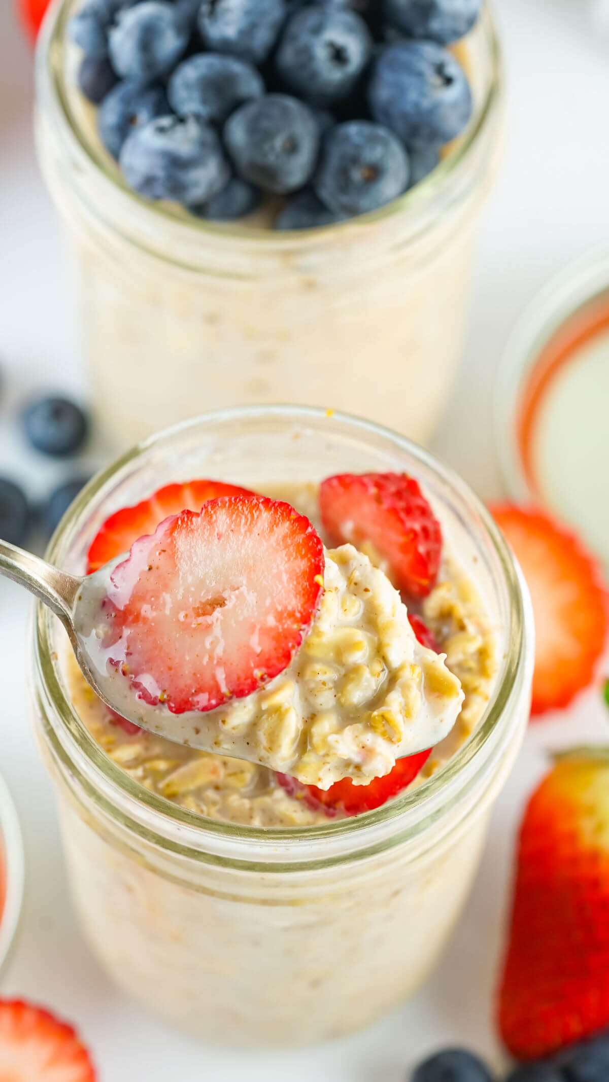Lactation overnight oats with sliced strawberries being lifted up on a spoon.