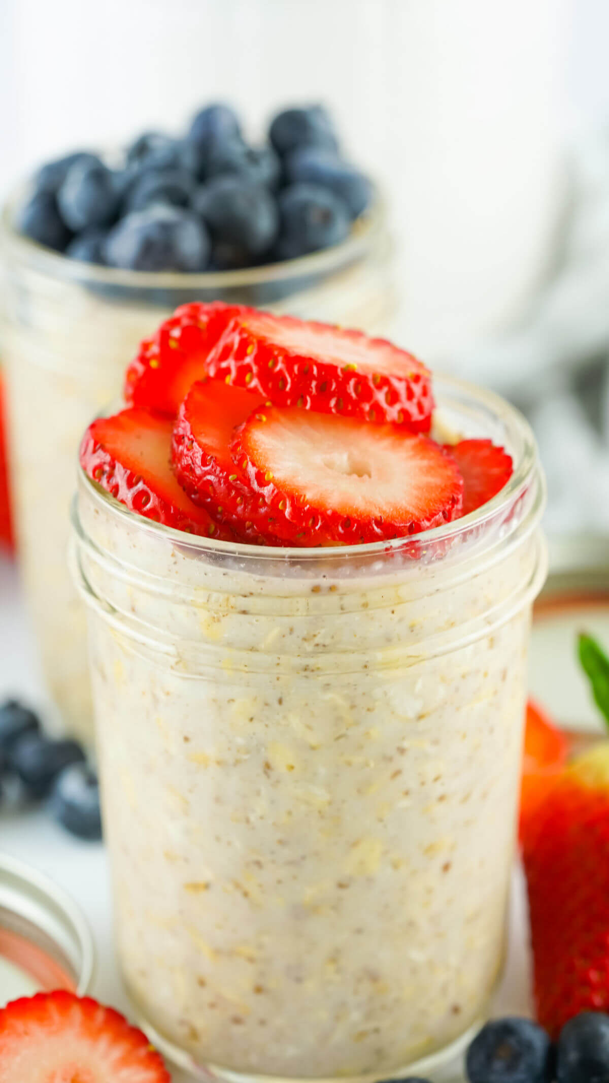 Lactation overnight oats in glass jars with blueberries and strawberries on top.