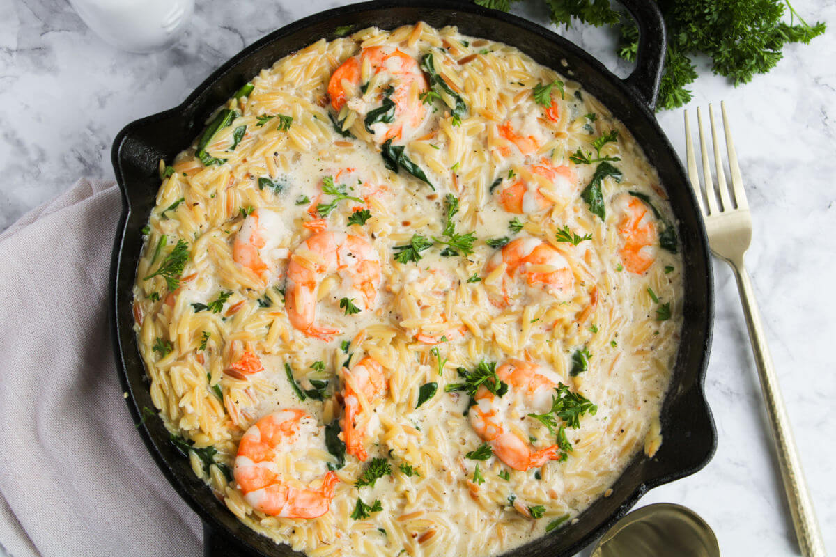Lemon garlic shrimp orzo in a cast iron skillet.