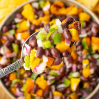 Mango black bean salsa in a bowl with tortilla chips on the side.