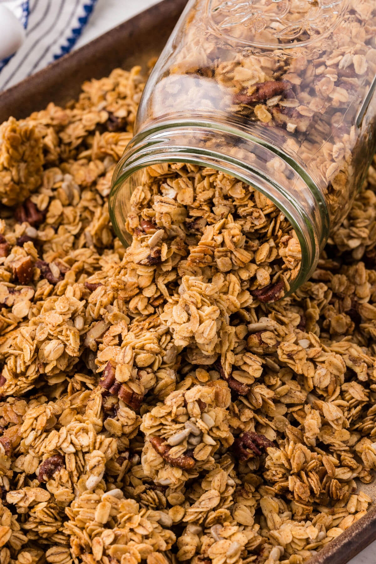 Maple pecan granola in a jar on a cookie sheet.