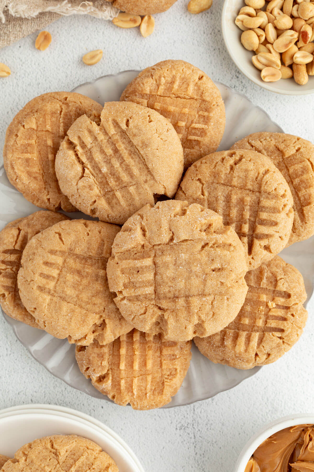Peanut Butter Sourdough Cookies piled on a plate, with shelled peanuts to the side.