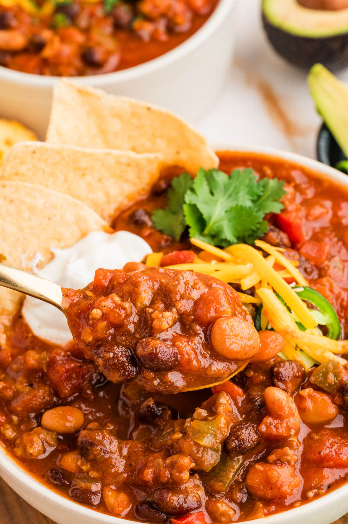 Pumpkin chili in a bowl with sour cream, cheese, and tortilla chips on top.