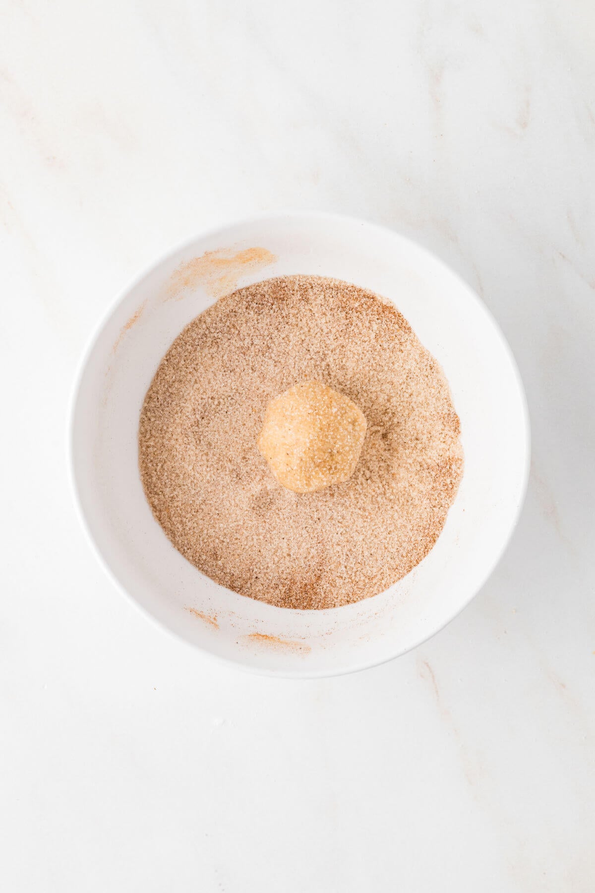 Rolling pumpkin pie spice cookies in cinnamon sugar mixture.
