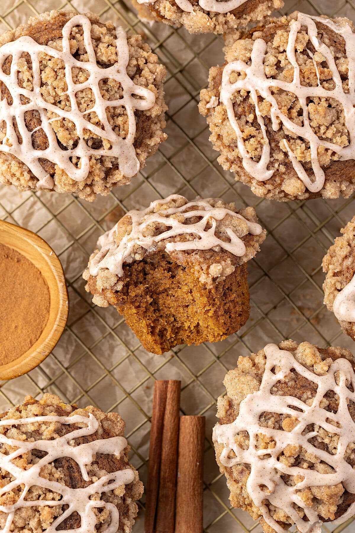 Sourdough pumpkin muffins on a wire cooling rack with a bite taken out of one muffins.