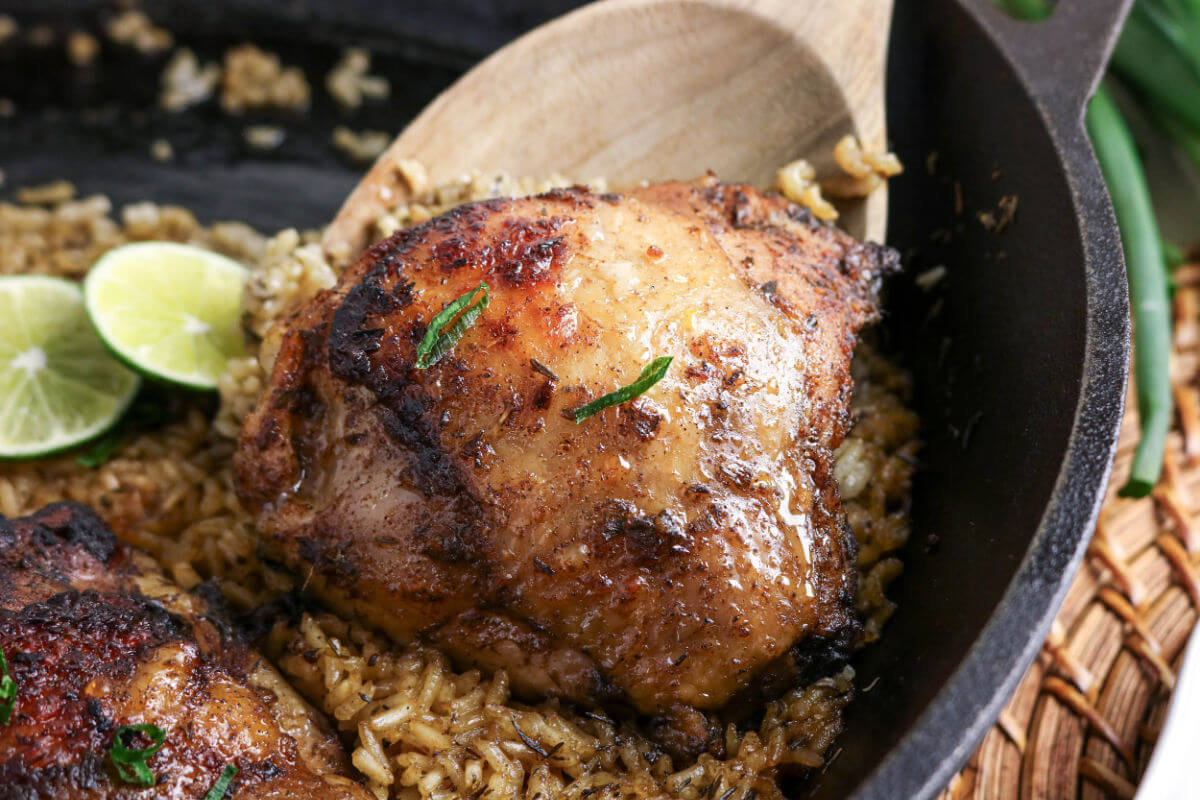Jerk chicken and rice recipe being served with a wooden spoon.
