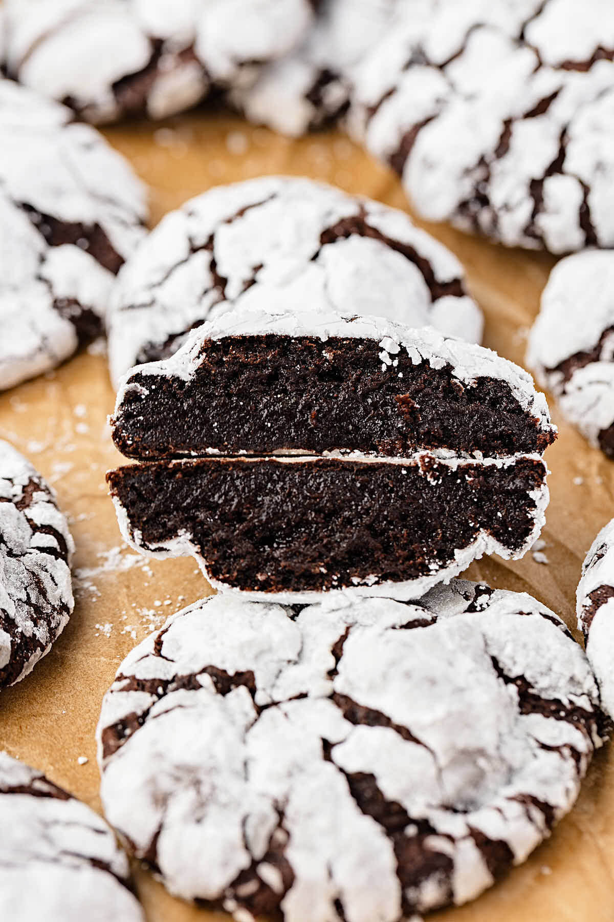 Sourdough chocolate crinkle cookies with one cookie cut in half to show the inside.