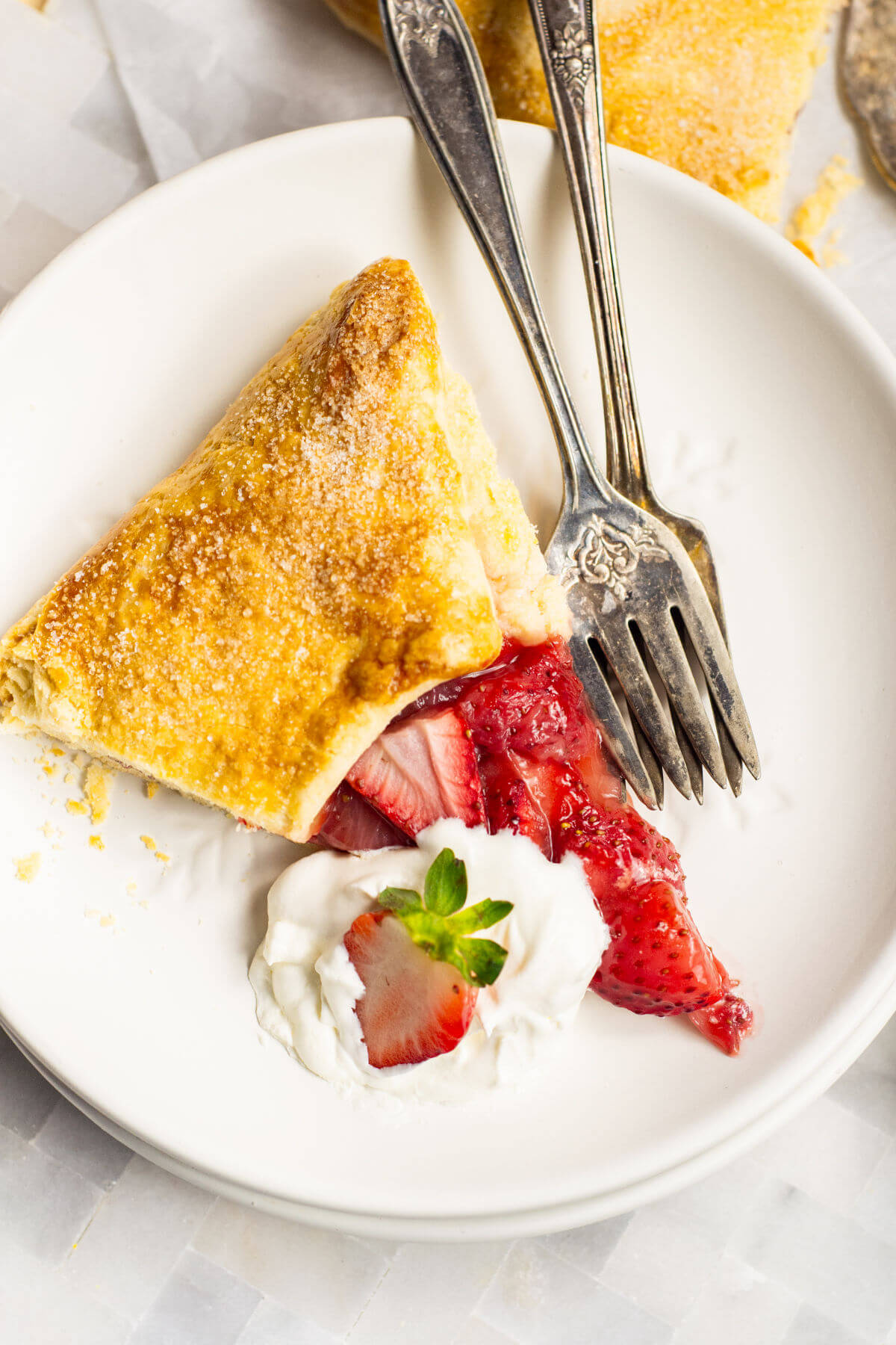 Slice of strawberry galette with whipped cream on a plate.