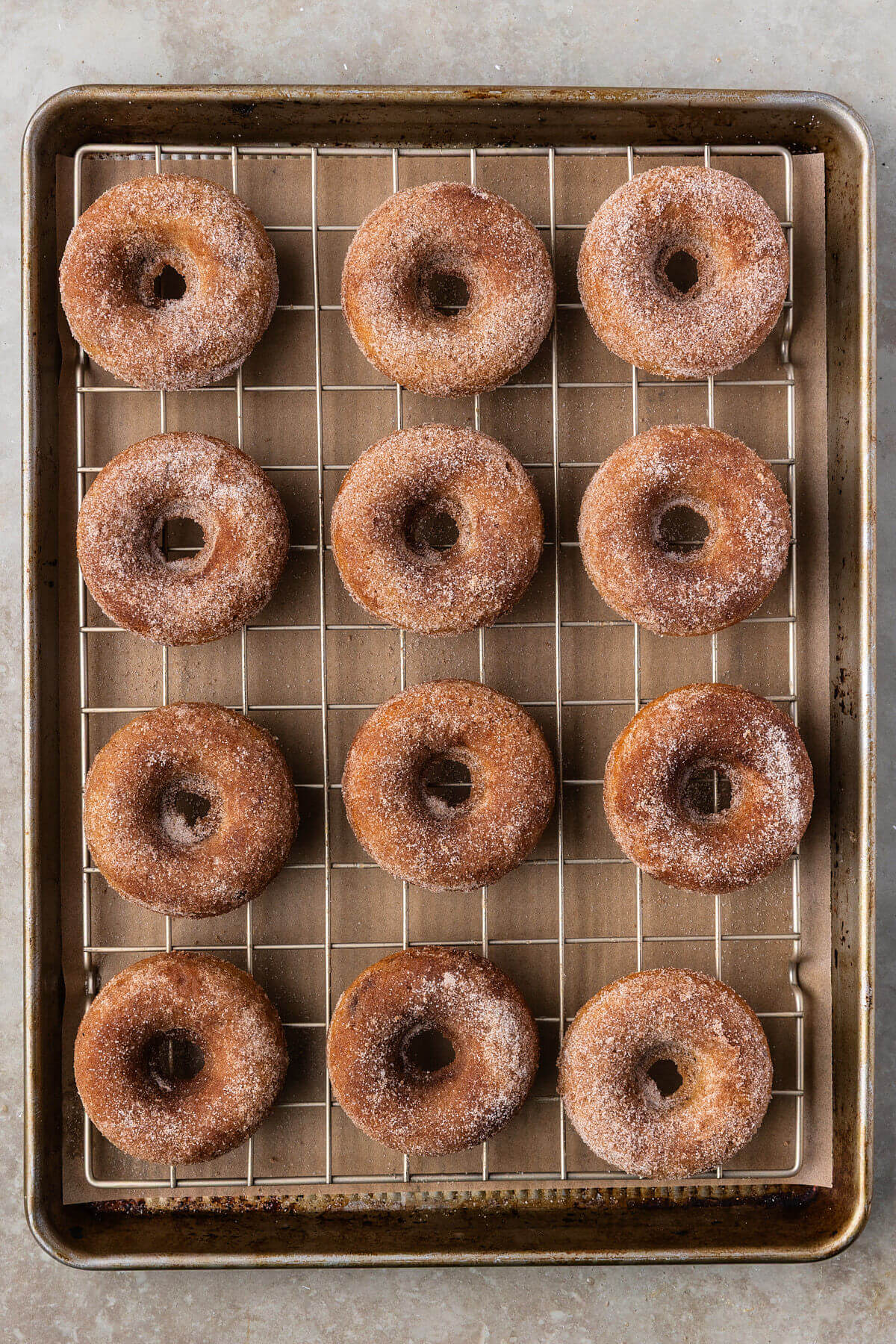 Sourdough apple cider donuts with cinnamon sugar coating on a wire rack.
