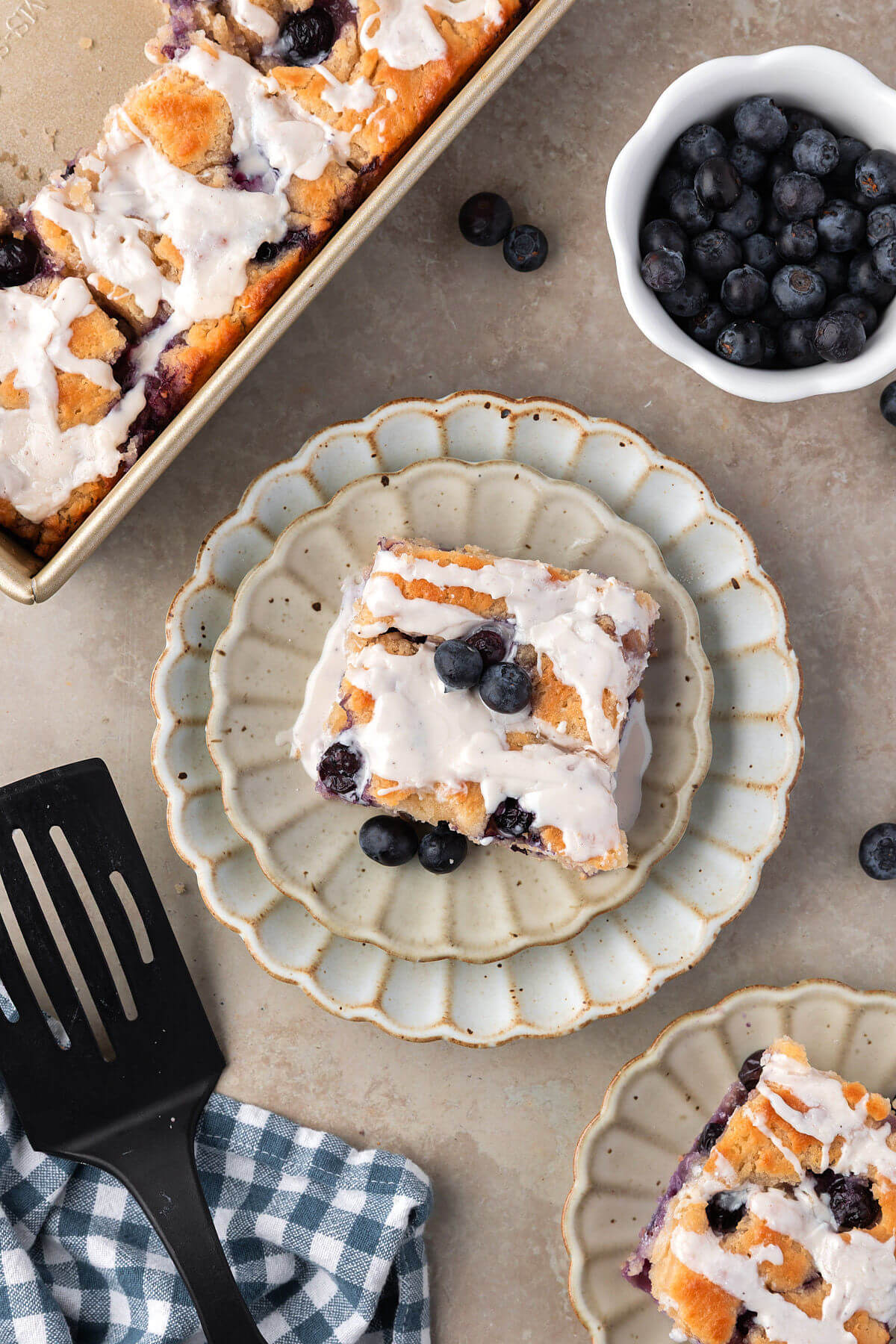 A pan of blueberry sourdough butter swim biscuits and one biscuit on a plate.
