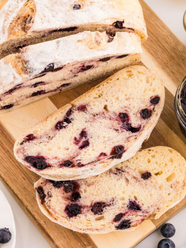 Sourdough lemon blueberry bread loaf on a wooden cutting board.