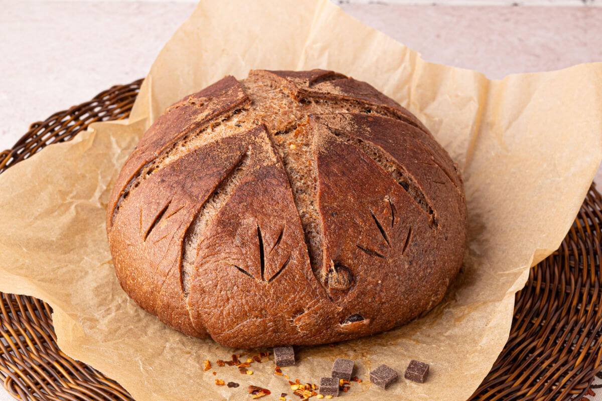 Loaf of sourdough chocolate chili bread on a piece of parchment paper.