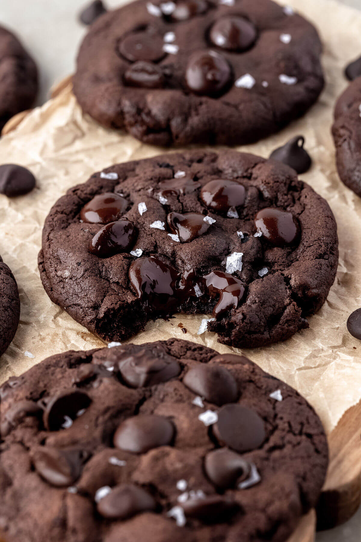Sourdough chocolate cookies on parchment paper with a bite out of the center cookie.