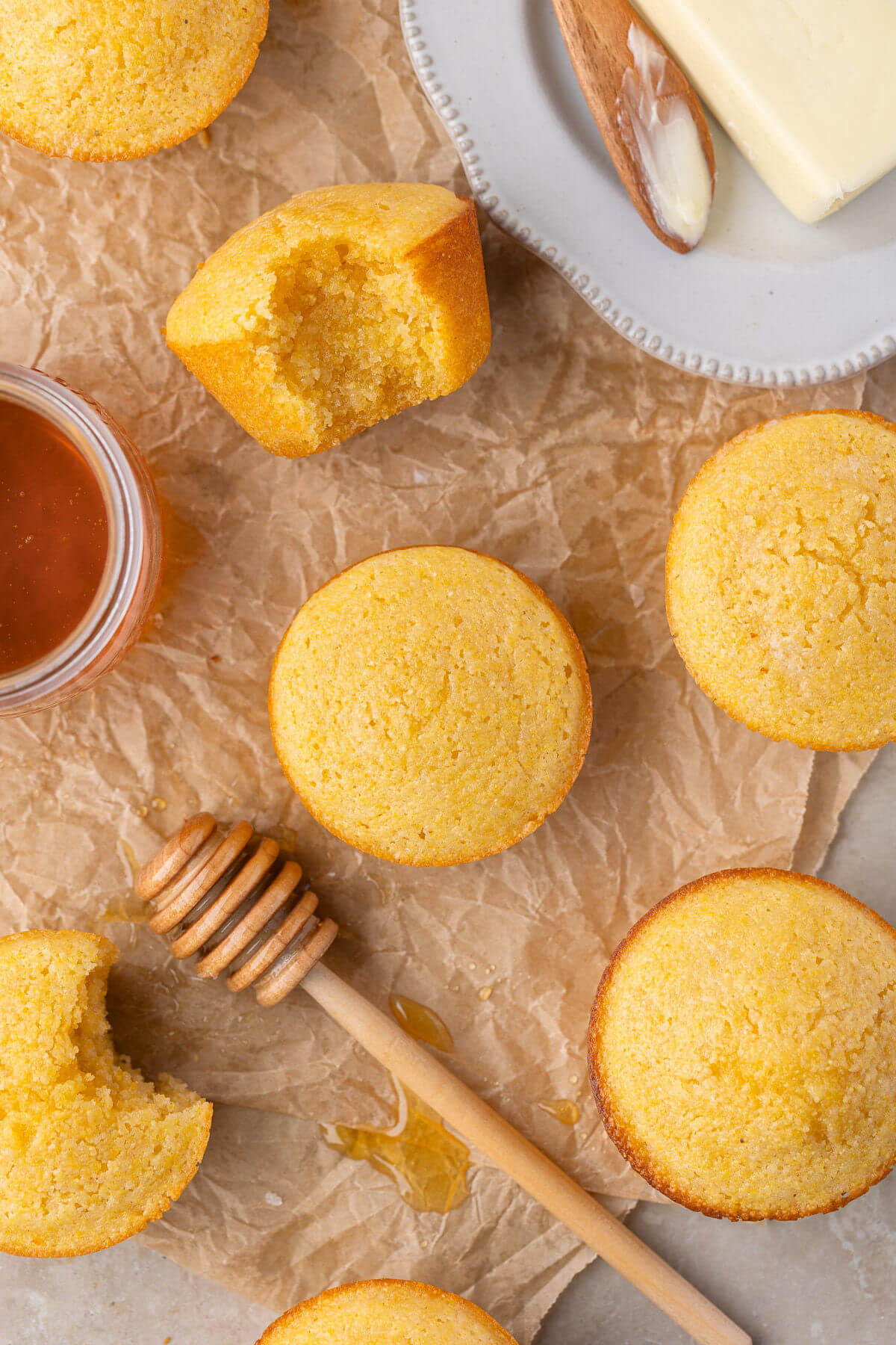 Sourdough cornbread muffins on parchment paper next to some honey.