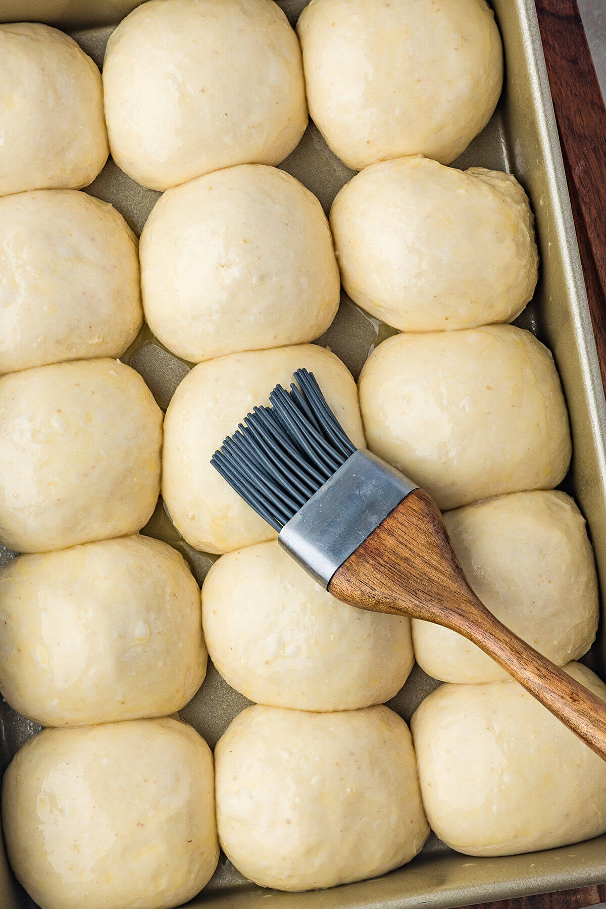 Brushing egg wash on top of the sourdough hawaiian rolls.