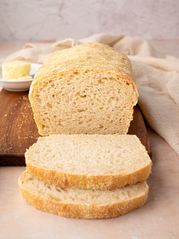 A freshly baked loaf of sourdough English muffin bread with two slices cut from the loaf.