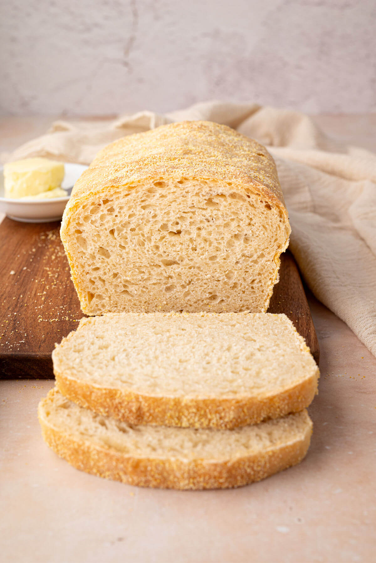 A freshly baked loaf of sourdough English muffin bread with two slices cut from the loaf.