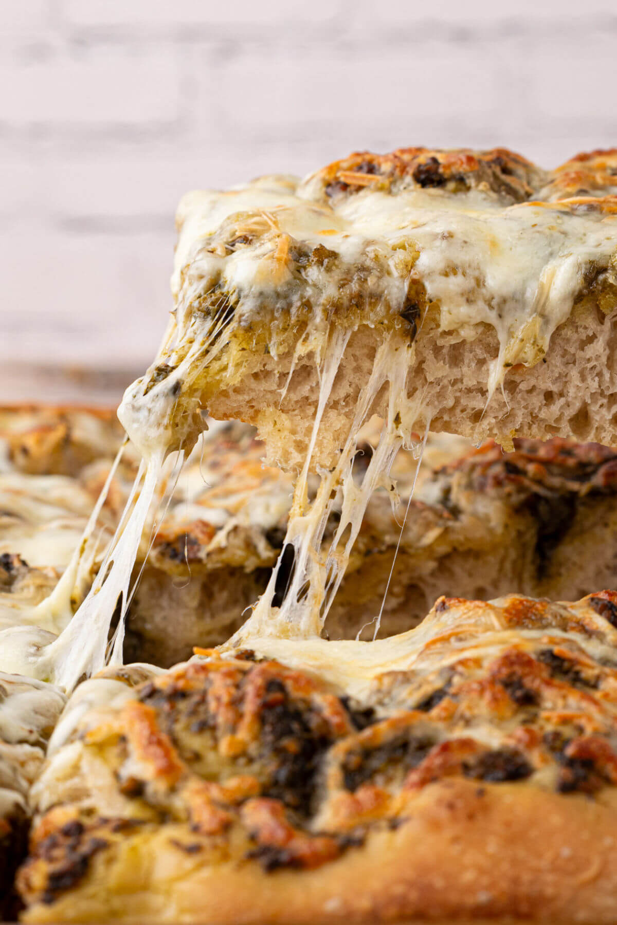 Sourdough focaccia pizza bianca being pulled from the pan with melted cheese stretching as the piece is removed.