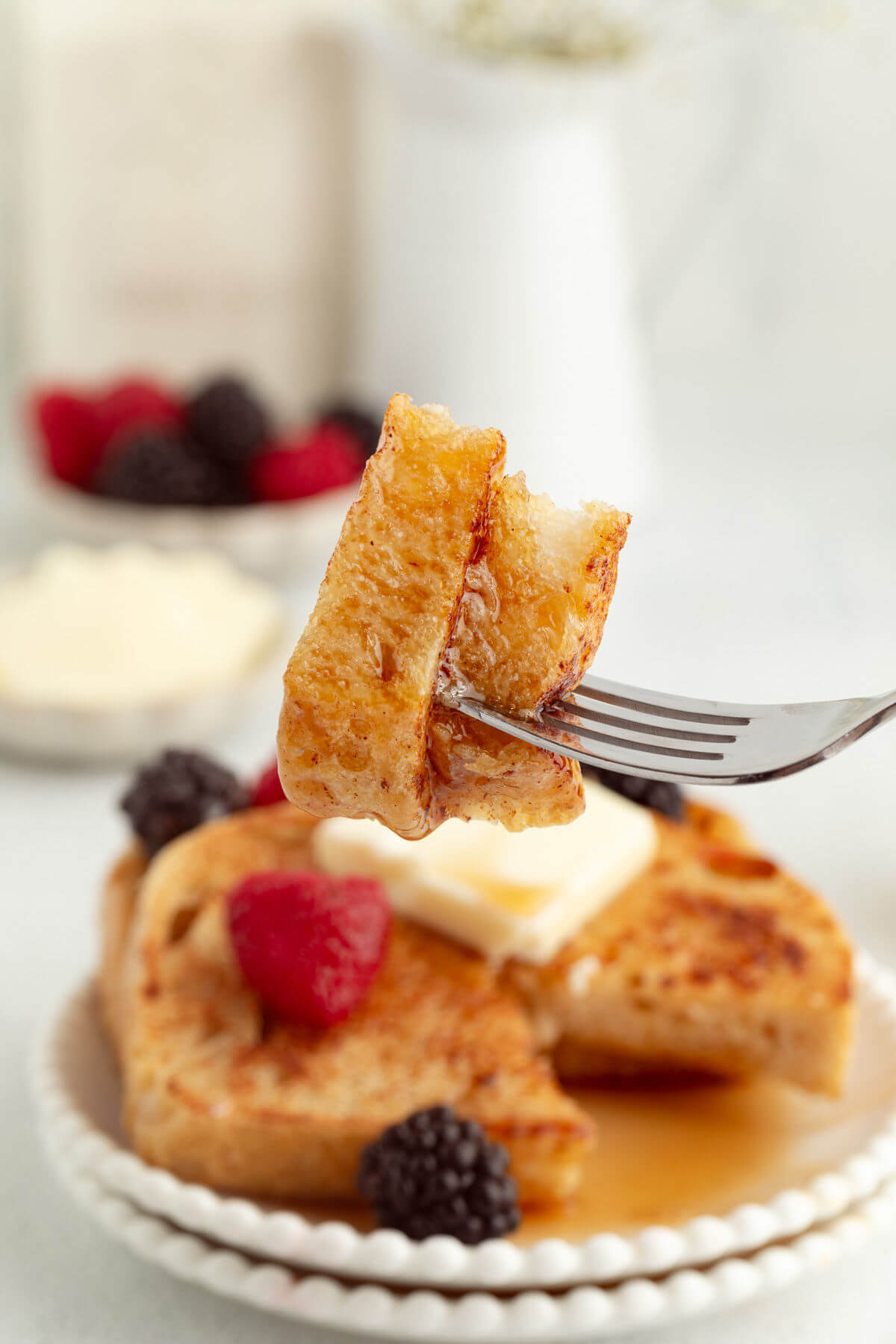 Sourdough French toast on a plate with butter and fresh berries.