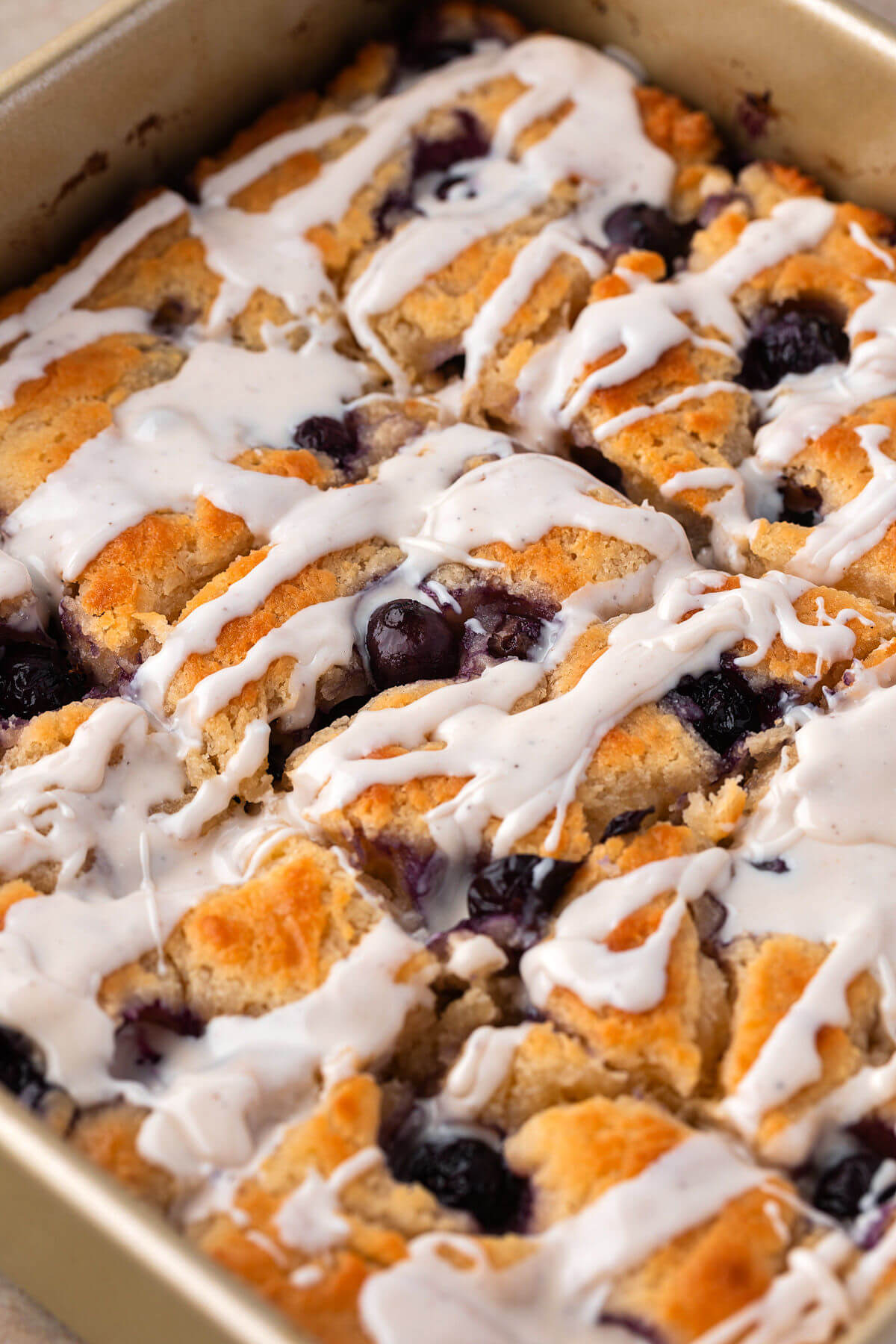 Pan of baked and glazed blueberry sourdough butter swim biscuits.