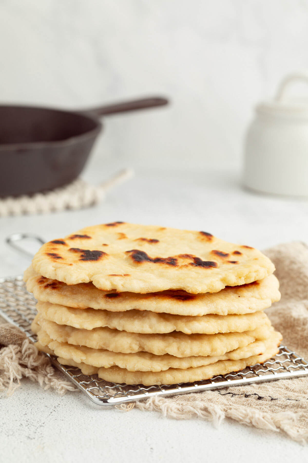 Sourdough naan in a stack on a wire cooling rack.