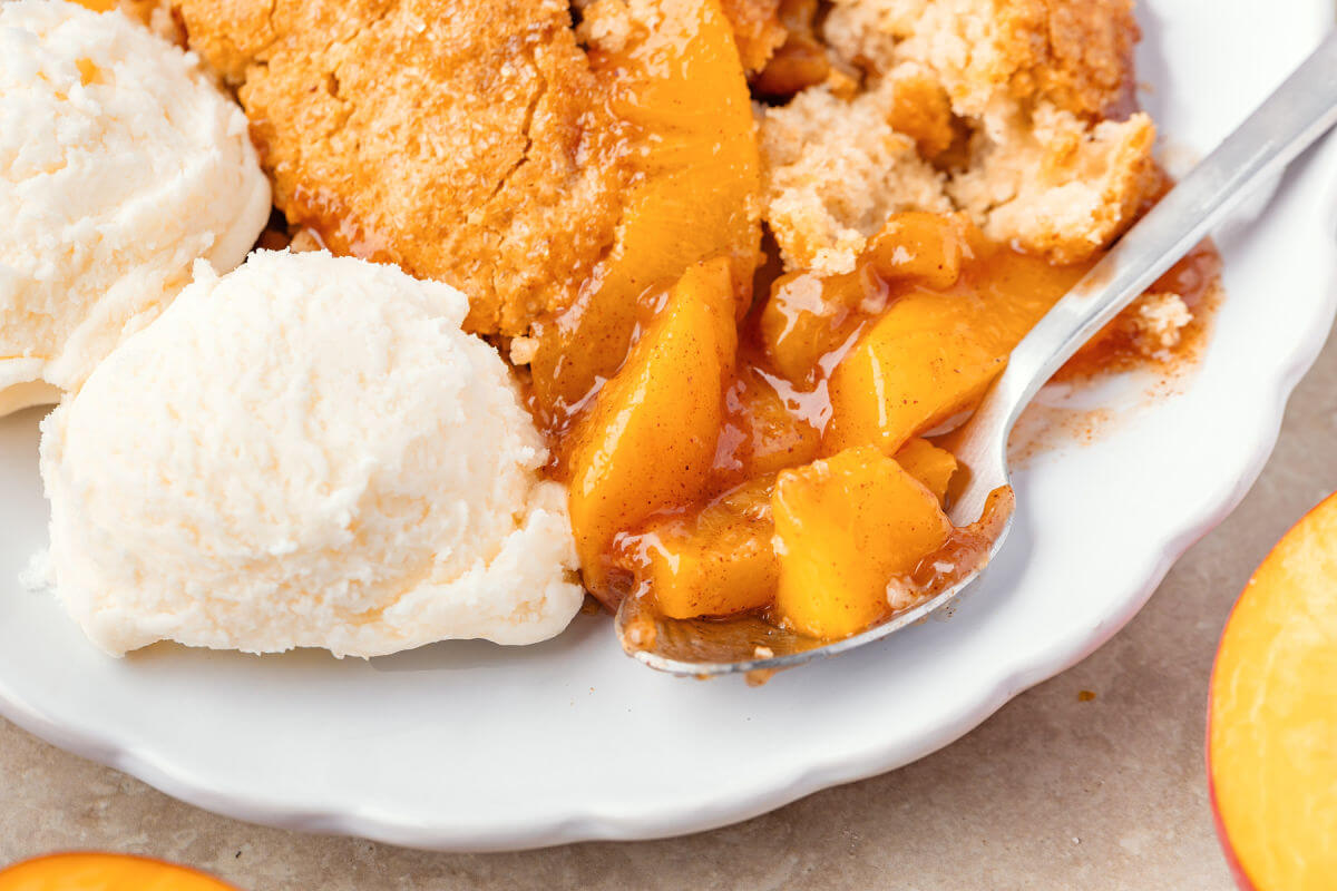 Sourdough peach cobbler on a plate with vanilla ice cream.