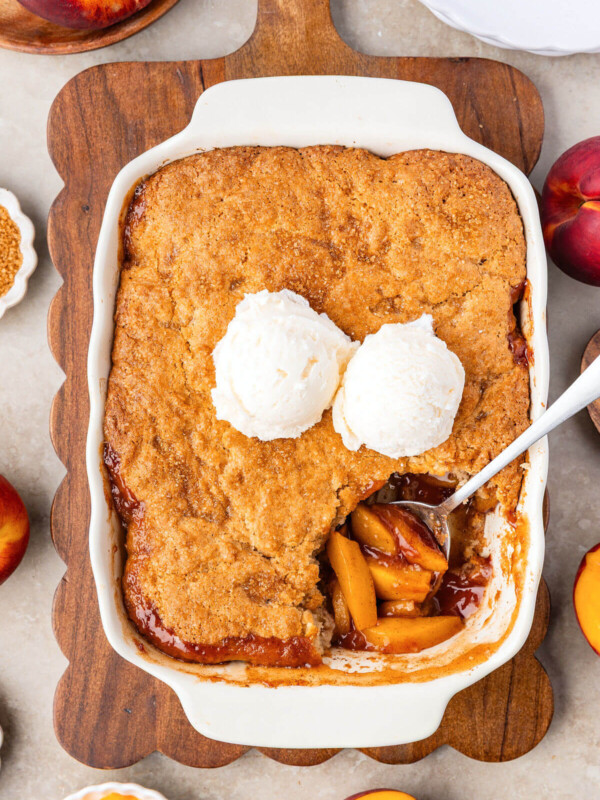 Sourdough peach cobbler in a baking dish with ice cream on top.