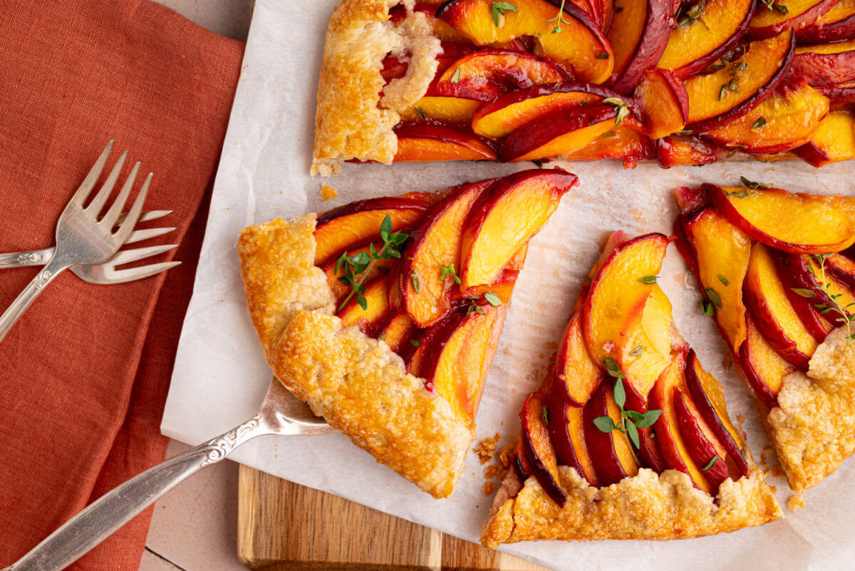 Sourdough peach galette being cut into slices.