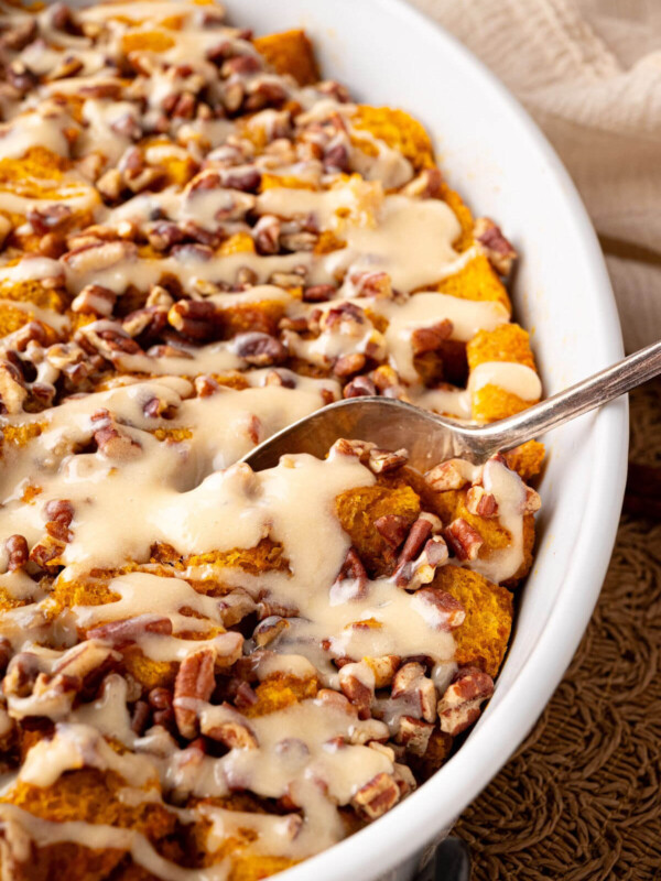 Sourdough pumpkin french toast casserole in a baking dish with frosting drizzled on top.
