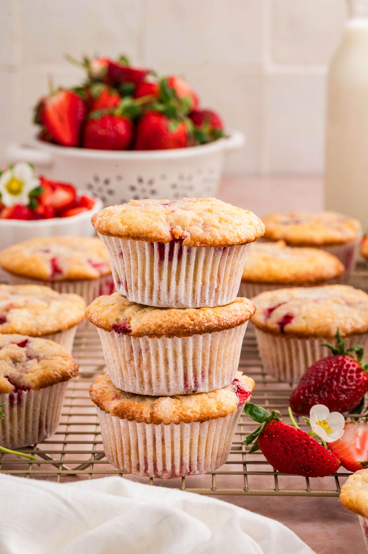 Pile of 3 strawberry muffins on a wire cooling rack.