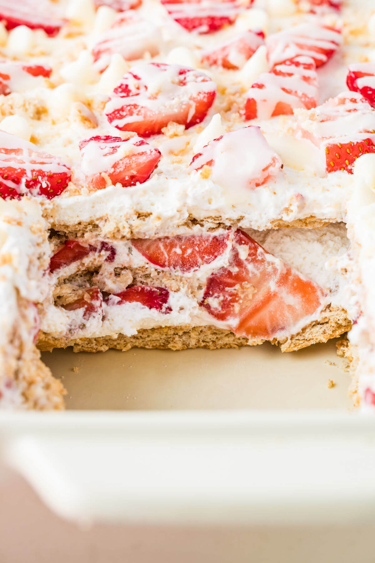 Strawberry icebox cake in a baking dish with piece cut out.