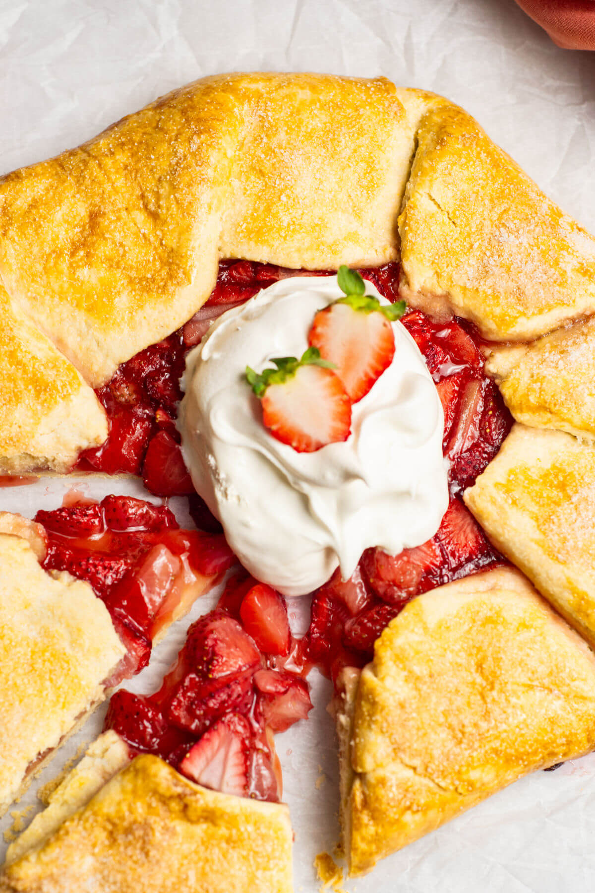 Strawberry galette after baking with whipped topping and two slices cut out, ready to serve.