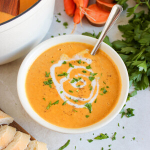 Sweet potato carrot soup in a serving bowl swirled with coconut cream.