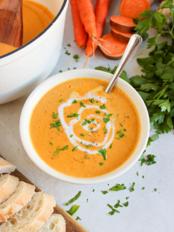 Sweet potato carrot soup in a serving bowl swirled with coconut cream.