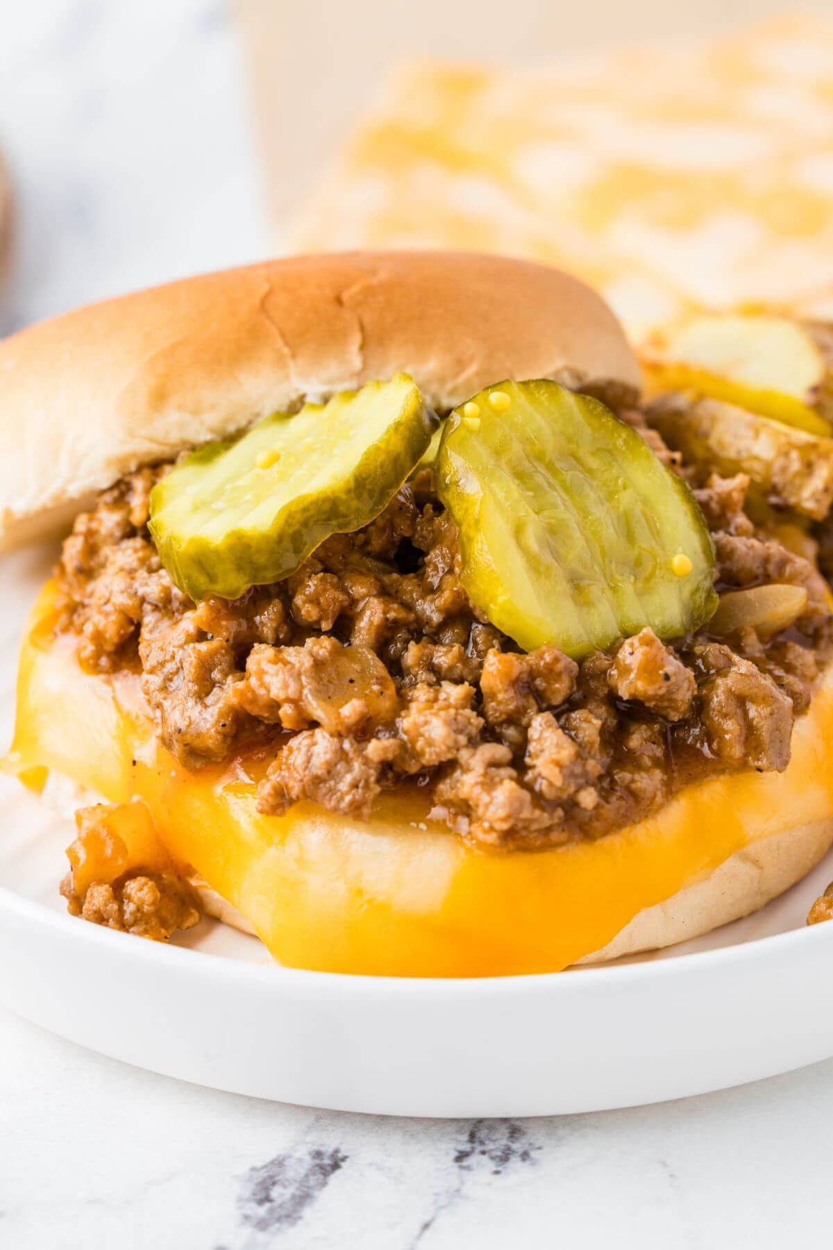 Turkey sloppy joes with pickles on a hamburger bun.