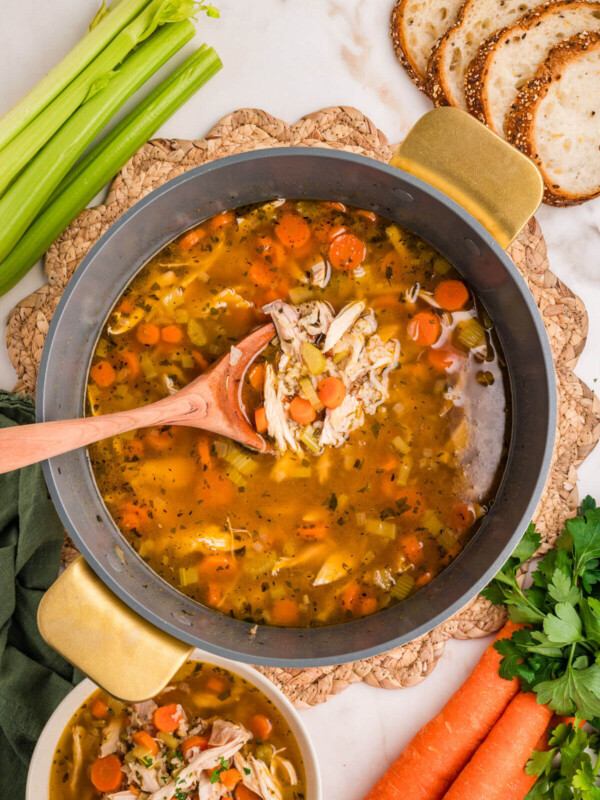 Turkey wild rice soup in a Dutch oven being served with a wooden spoon.