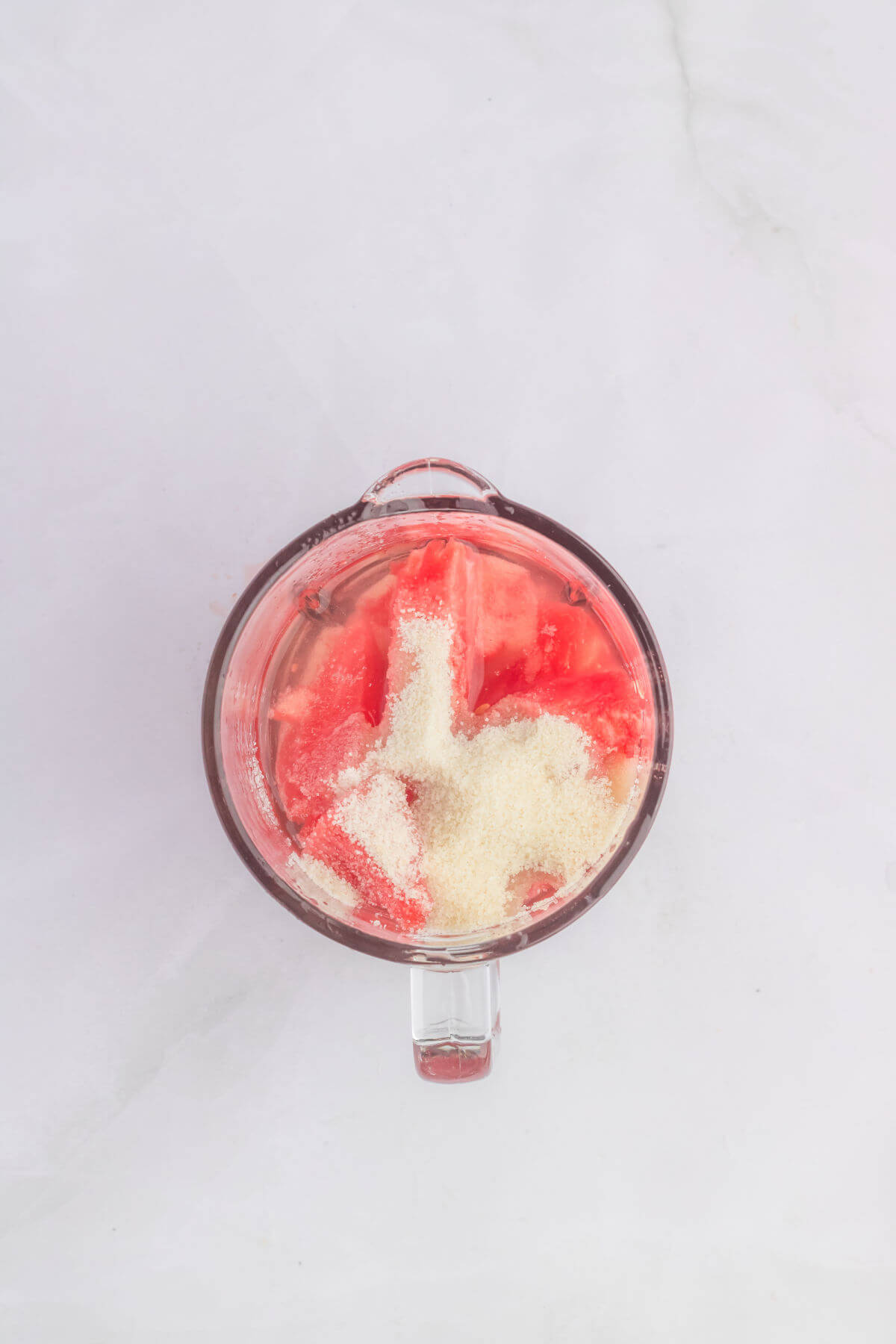 Glass blender container with ingredients for making watermelon lemonade.