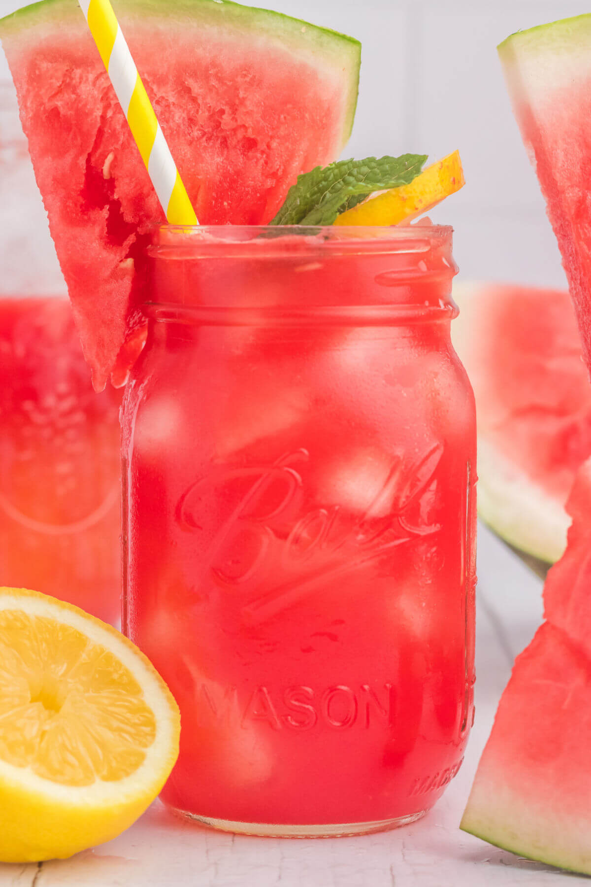 Watermelon lemonade in a mason jar with a slice of watermelon and a fresh lemon.