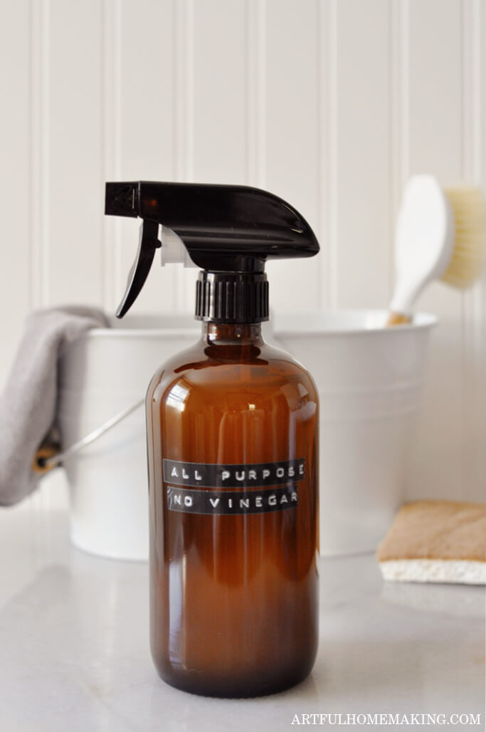 amber glass spray bottle on countertop with natural sponge and scrub brush