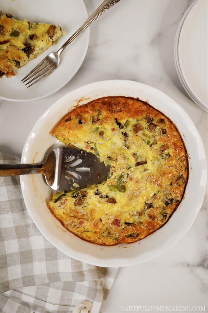 white ceramic pie dish with a crustless quiche baked in it on a marble countertop