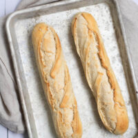 French baguettes on a metal baking sheet after baking.