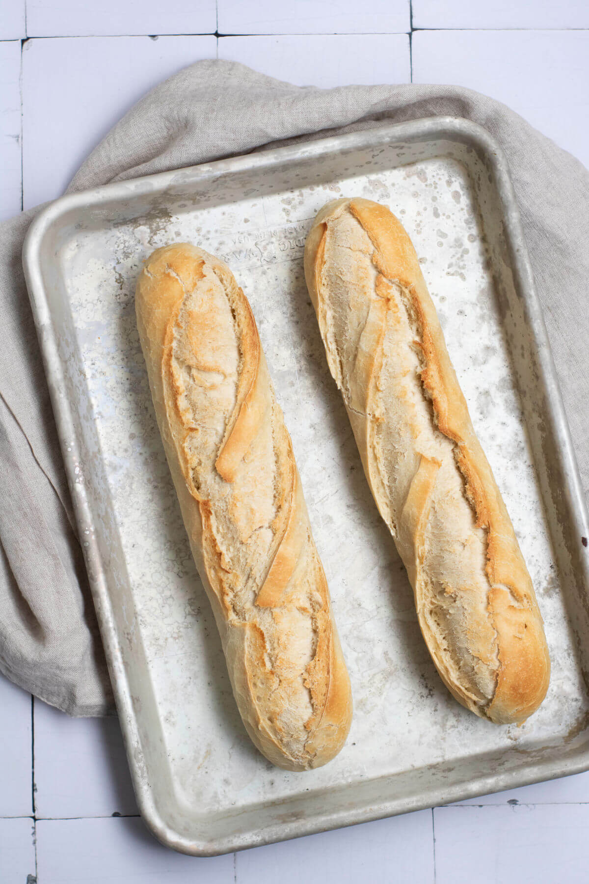 French baguettes on a metal baking sheet after baking.