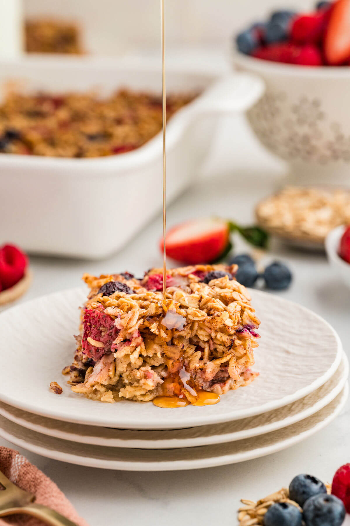 Baked oatmeal on a plate with maple syrup being poured onto it.